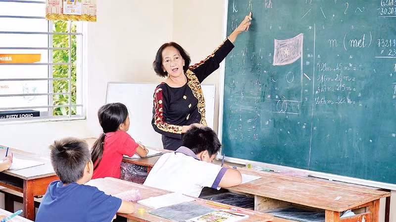Cô Thủy tận tụy hướng dẫn các học trò viết chữ. Cô Thủy tận tụy hướng dẫn các học trò viết chữ.