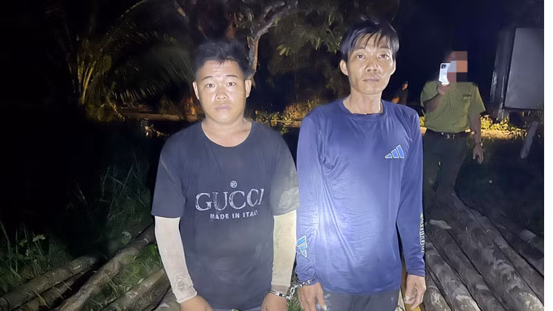 Hai trong nhóm các đối tượng bị bắt khi đang khai thác gỗ trái phép. (Ảnh: Kiểm lâm cung cấp).