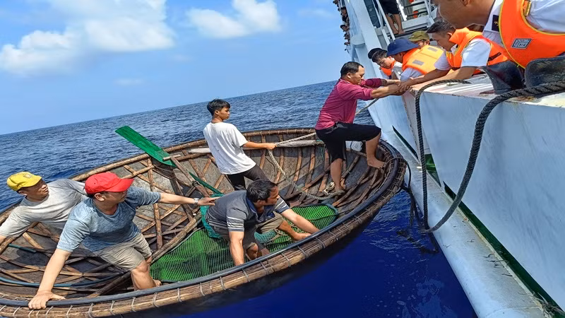 Đón ngư dân từ thuyền thúng lên tàu để vào bờ.