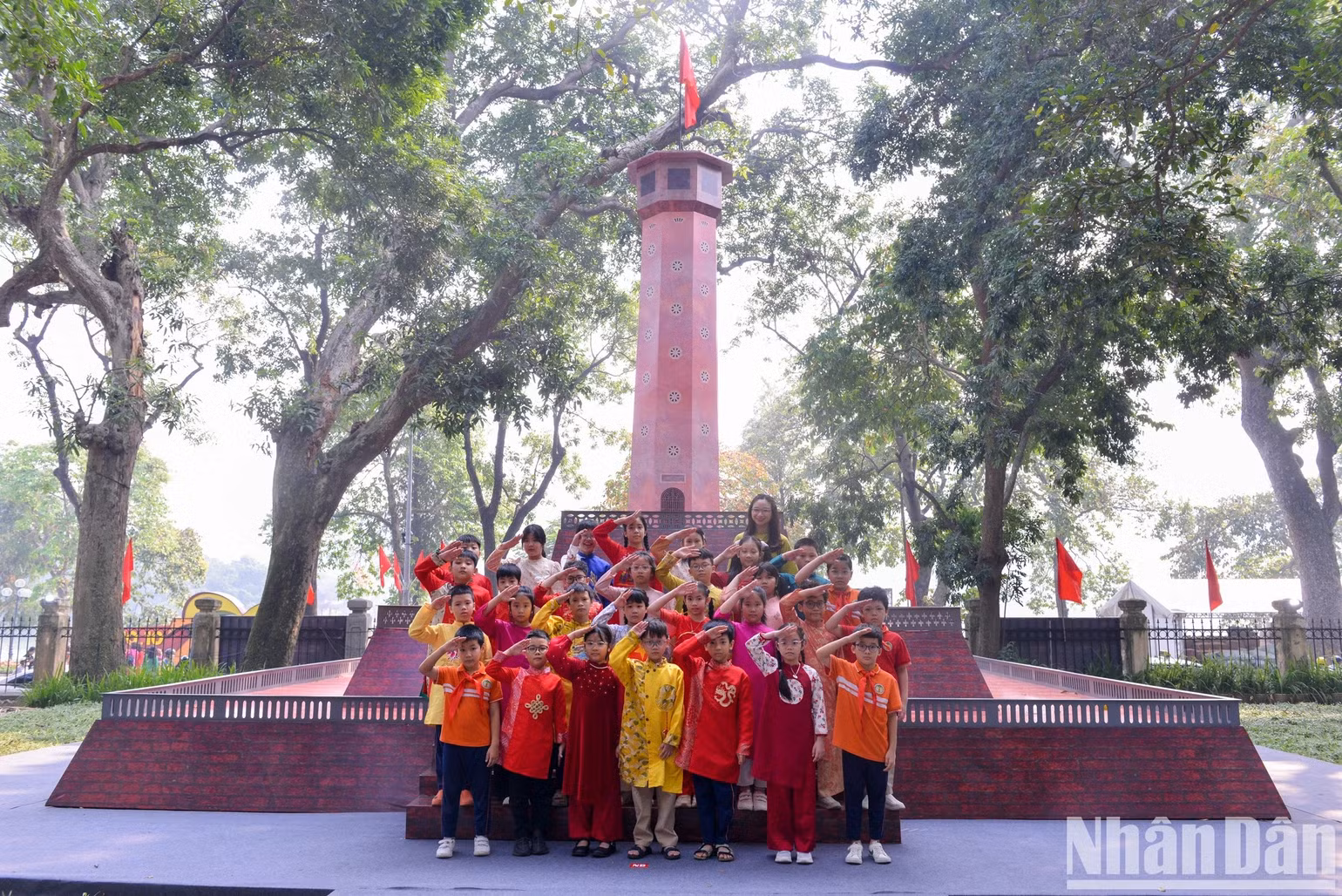 Cô và trò trường Tiểu học Tràng An (quận Hoàn Kiếm) thực hiện nghi thức chào cờ tại triển lãm tương tác Cột cờ Hà Nội tại trụ sở Báo Nhân Dân. Ảnh: Thế Đại