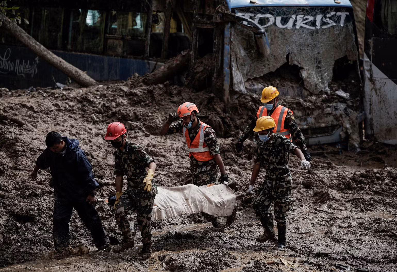 Cảnh sát Nepal đưa các nạn nhân trong vụ xe buýt bị bùn vùi lấp tại Kathmandu ra khỏi hiện trường. (Ảnh: Reuters)