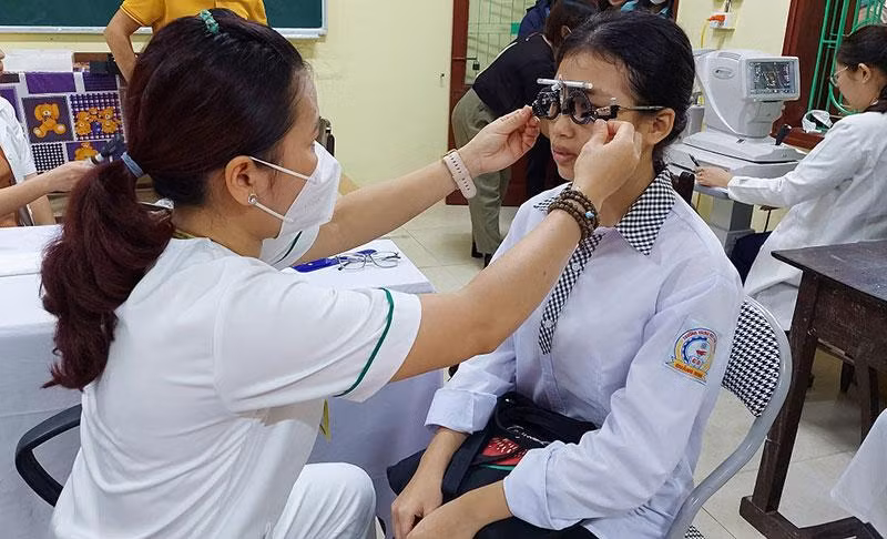 Các y, bác sĩ khám mắt cho học sinh.