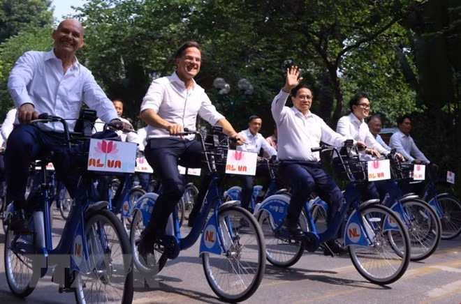 Thủ tướng Phạm Minh Chính cùng Thủ tướng Hà Lan Mark Rutte đạp xe trên đường phố Hà Nội. (Ảnh: Văn Điệp/TTXVN)