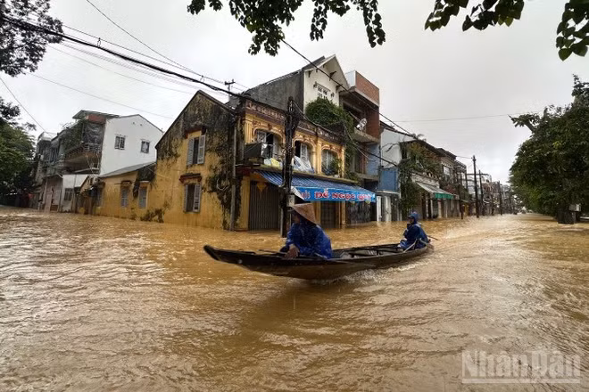 Nước ngập sâu, người dân sử dụng thuyền để di chuyển trong đô thị.