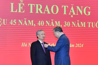 Tổng Bí thư Tô Lâm gắn Huy hiệu 45 năm tuổi đảng tặng đồng chí Trần Quốc Vượng. (Ảnh: ĐĂNG KHOA)