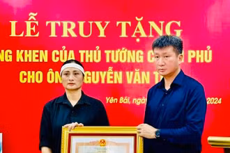Chủ tịch Ủy ban nhân dân tỉnh Yên Bái Trần Huy Tuấn trao Bằng khen của Thủ tướng Chính phủ cho gia đình anh Nguyễn Văn Thi. (Ảnh: THANH SƠN)