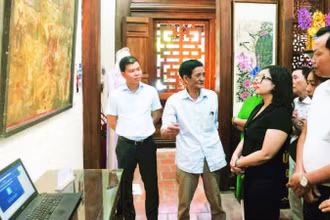 Nghệ nhân Lê Đình Nghiên (thứ hai từ trái sang) giới thiệu về tranh Hàng Trống trong triển lãm Phục hồi tại đình Nam Hương, quận Hoàn Kiếm.