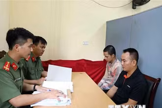 Lực lượng chức năng lấy lời khai bị can Nguyễn Quang D. (áo đen) và bị can Đinh Tiến S. (áo kẻ). (Ảnh: Phạm Kiên/TTXVN)