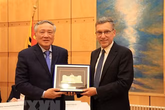 Chánh án Tòa án Nhân dân Tối cao Nguyễn Hòa Bình (trái) tặng quà lưu niệm cho ông Christian Coquoz, Chánh án Tòa án bang Geneva. (Ảnh: TTXVN)