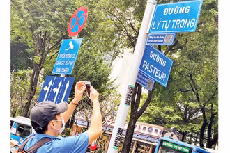 Một du khách tra cứu thông tin tên đường từ mã QR gắn ở giao lộ Lý Tự Trọng-Pasteur, quận 1, TP Hồ Chí Minh.