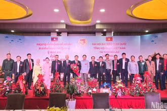 Đại sứ Nguyễn Bá Hùng tặng hoa chúc mừng Chủ tịch và Ban Chấp hành khóa III Tổng hội người Việt Nam tại Lào. (Ảnh: Trịnh Dũng)
