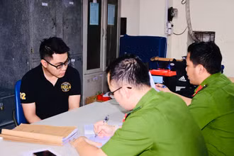 Nguyễn Tường Lâm (áo đen) bị bắt giữ tại cơ quan công an.