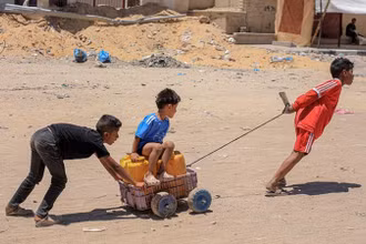 Các em nhỏ vận chuyển nước tại Khan Younis, Dải Gaza, ngày 31/5/2024. (Ảnh: THX/TTXVN)