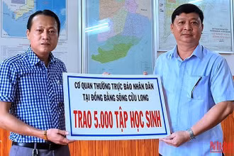 Chủ tịch Ủy ban nhân dân huyện Đầm Dơi (bìa phải) tiếp nhận 5.000 tập hỗ trợ từ Cơ quan Thường trực Báo Nhân Dân tại vùng đồng bằng sông Cửu Long.