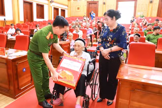 Đại tá Đỗ Tiến Thùy, Phó Giám đốc Công an tỉnh Tuyên Quang tặng quà Mẹ Việt Nam Anh hùng, mẹ liệt sĩ tham gia lấy mẫu.
