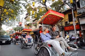 Du khách nước ngoài sử dụng xích-lô thưởng ngoạn nét đẹp cổ kính của Phố cổ Hà Nội. (Ảnh: TTXVN)