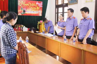Phan Thị Anh (bên trái) đang nghe cơ quan chức năng tống đạt quyết định khởi tố.