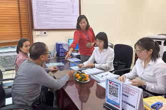 Cán bộ ngân hàng hướng dẫn người dân mở tài khoản để thực hiện chi trả an sinh xã hội không dùng tiền mặt. 