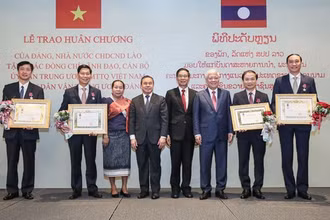 Chủ tịch Ủy ban Trung ương Mặt trận Lào xây dựng đất nước Sinlavong Khoutphaythoune và Chủ tịch Ủy ban Trung ương MTTQ Việt Nam Đỗ Văn Chiến chụp ảnh lưu niệm với các cá nhân được nhận Huân chương Ít-xa-la hạng II, III 