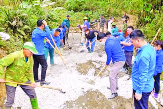 Cán bộ, hội viên các tổ chức giúp nhân dân thôn Bản Lằn trộn bê-tông làm đường giao thông thôn, bản.