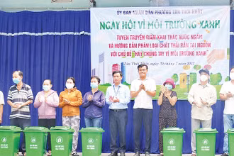 Ðại diện UBND phường Tân Thới Nhất (Quận 12) tặng thùng rác cho người dân. (Ảnh CTV)