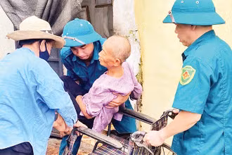 Chính quyền địa phương giúp đỡ những người già yếu, tàn tật sơ tán khỏi mưa lũ. 