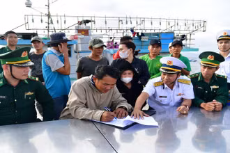Bàn giao tàu cá BĐ 98833TS cùng 14 ngư dân cho cơ quan chức năng. (Ảnh: NGUYỄN NAM)