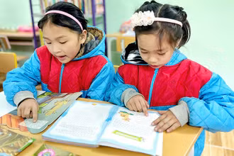 Các em học sinh đọc sách tại thư viện của Trường Phổ thông dân tộc bán trú Tiểu học Ngam La. (Ảnh NFVC)