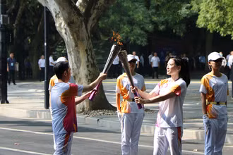 Hai thành viên rước đuốc trao truyền lửa thiêng ASIAD 19. (Ảnh: people.com.cn)