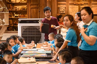 Nghệ nhân Nguyễn Tấn Phát hướng dẫn các em nhỏ thực hành làm tranh in khắc gỗ.
