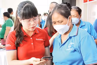Nhân viên Agribank Chi nhánh Nhà Bè hướng dẫn người dân huyện Nhà Bè (Thành phố Hồ Chí Minh) thao tác thanh toán không dùng tiền mặt. (Ảnh Thế Anh)