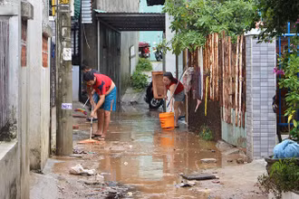 Người dân dọn dẹp bùn đất sau trận lụt.