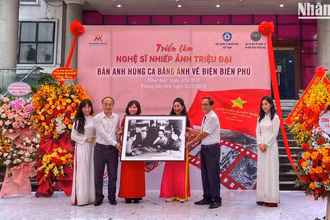Đạo diễn Triệu Tuấn (người cầm ảnh bên phải) đại diện gia đình cố Nghệ sĩ nhiếp ảnh Triệu Đại trao tặng bộ ảnh cho Bảo tàng Phụ nữ Việt Nam.