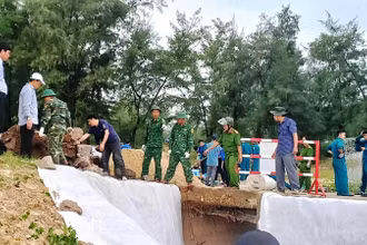 Các cán bộ, chiến sĩ Biên phòng cùng lực lượng địa phương khắc phục sự cố sạt lở kè biển do mưa lũ ở xã Phú Diên (huyện Phú Vang). 