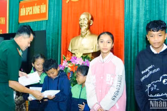 Đại diện Đồn Biên phòng Cửa khẩu Hồng Vân trao kinh phí hỗ trợ cho các em học sinh. (Ảnh: Võ Tiến).