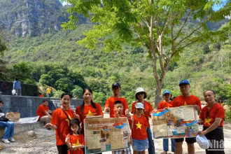 Du khách mang theo phụ san của Báo Nhân Dân về Chiến dịch Hồ Chí Minh, check-in tại thác Bản Giốc, xã Đàm Thủy, huyện Trùng Khánh, tỉnh Cao Bằng.