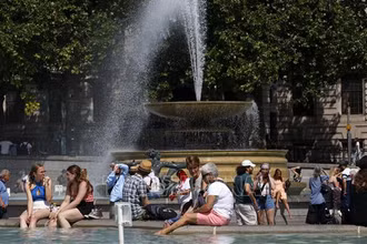 Người dân tránh nóng bên đài phun nước tại Quảng trường Trafalgar ở thủ đô London, Anh, ngày 17/6/2022. (Ảnh: AFP/TTXVN)
