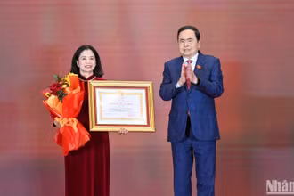 Chủ tịch Quốc hội Trần Thanh Mẫn trao Huân chương Lao động hạng Nhất và tặng hoa chúc mừng đồng chí Lê Thị Nguyệt. (Ảnh: Duy Linh)