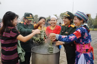 Đồng bào các dân tộc đang hoạt động tại "Làng" cùng các chiến sĩ tham gia luộc bánh chưng. (Ảnh: PH)
