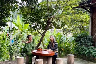 Trung tá Ating Chơn trao đổi với già làng Bríu Pố về công tác giữ gìn an ninh trật tự tại địa phương
