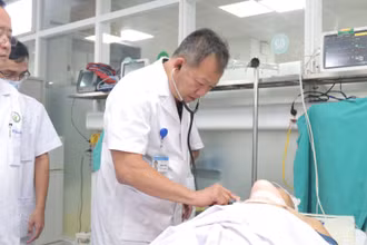 Tiến sĩ Dương Đức Hùng, Giám đốc Bệnh viện Hữu nghị Việt Đức khám cho bệnh nhân trước khi đưa vào phòng mổ. (Ảnh: BVCC)