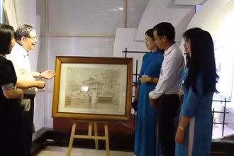 Ông Chu Đức Tính (người thứ 2 bên trái) giới thiệu về bức tranh thêu “Chùa Một Cột”.
