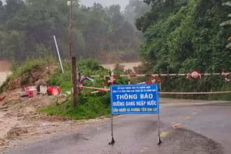Cắm biển báo và giăng dây cấm người qua lại điểm ngập nước trên tuyến 14B, đoạn qua xã Trà Tân.