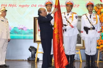 Chủ tịch nước Nguyễn Xuân Phúc gắn danh hiệu Anh hùng Lực lượng vũ trang nhân dân lên Cờ truyền thống của đơn vị. (Ảnh: Báo CAND)