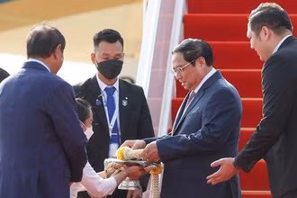 Thủ tướng Phạm Minh Chính nhận hoa chúc mừng tại sân bay quốc tế Phnom Penh. (Ảnh: VGP/Nhật Bắc)
