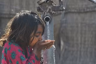 Em nhỏ uống nước từ vòi nước công cộng ở Lahore, Pakistan. (Ảnh: AFP/TTXVN)