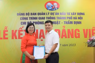 Bí thư Chi bộ Phòng Kỹ thuật-Thẩm định (Ban Quản lý dự án đầu tư xây dựng công trình giao thông thành phố Hà Nội) trao Quyết định kết nạp đảng cho đồng chí Bùi Thị Phương Ngọc. Ảnh: Linh Nguyễn