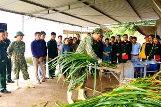 Cán bộ Căn cứ Hậu cần 1, Cục Hậu cần Quân khu 4 hướng dẫn người dân ở bản Mó, xã Nghĩa Xuân, huyện Quỳ Hợp (Nghệ An) cách chế biến thức ăn chăn nuôi bò.