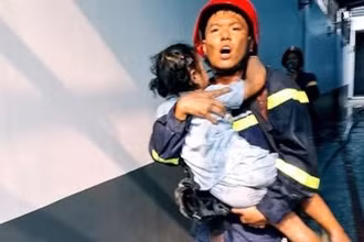 Lực lượng cứu hộ bế một em bé ra ngoài hiện trường vụ cháy.