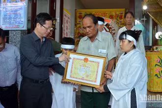 Chủ tịch UBND tỉnh Bình Thuận Đoàn Anh Dũng (áo sậm màu) trao cho thân nhân gia đình anh Nguyễn Hữu Đốn Bằng khen truy tặng anh Nguyễn Hữu Đốn vì đã có hành động dũng cảm quên mình cứu người, cứu tài sản của nhân dân.